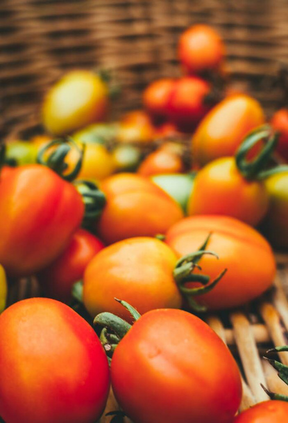 A vertical closeup shot of fresh tomatoes in a basket with a blurred background - Foto, imagen