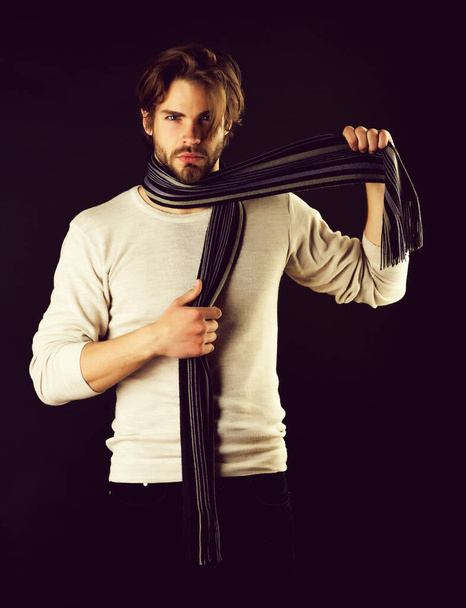 Serious guy with beard and moustache takes striped scarf - Foto, imagen