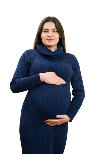 Proud pregnant woman wearing turtle-neck dress and holding her belly isolated on white background as pregnancy fashion concept - Foto, Imagen