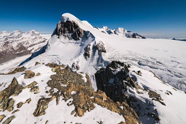 Una impresionante toma de las montañas rocosas cubiertas de nieve bajo un cielo azul
 - Foto, imagen