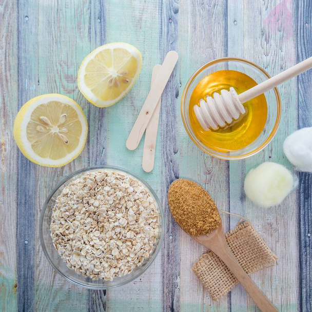 An overhead shot of natural skincare product ingredients: lemon, honey, oat flakes and brown sugar - Photo, image