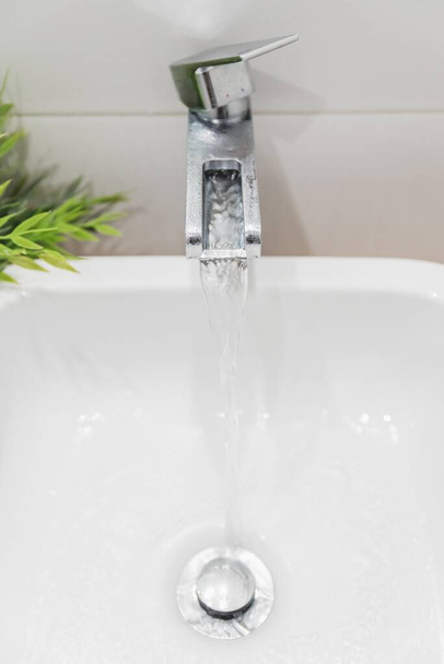 The water running  from the modern styled faucet in the sink - Zdjęcie, obraz