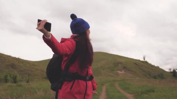 gratis Jonge meisje toeristische blogger legt selfie video 's aan de voet van de bergen met behulp van een smartphone met een prachtig landschap op de achtergrond. Gezond vrolijke vrouw reist en fotografie natuur per telefoon - Video