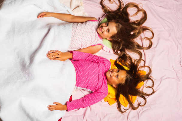 Schoolgirls having pajama party holding hands. Childhood and good morning - Фото, изображение