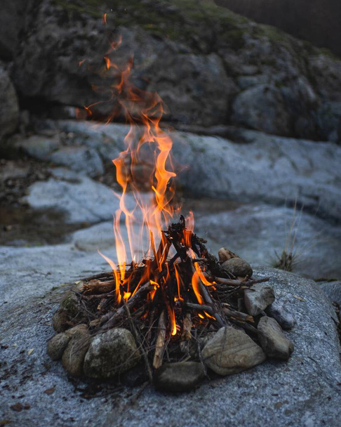 A vertical shot of small bonfire with beautiful flames on the rocks - Фото, зображення