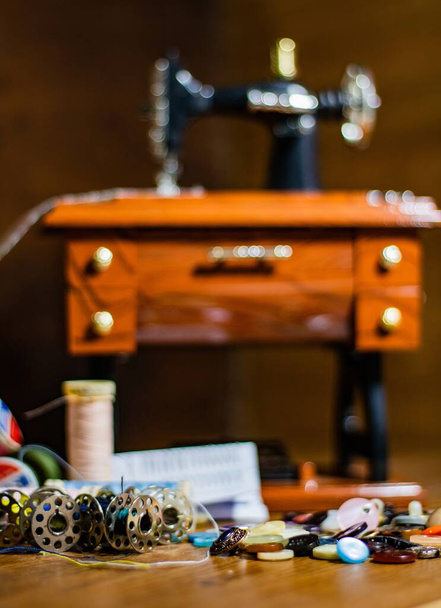 A selective focus shot of several spools of colorful threads and a sewing machine - Zdjęcie, obraz