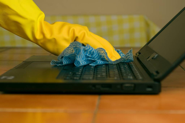 A person's hands wearing gloves cleaning the laptop for coronavirus bacteria prevention - Fotó, kép