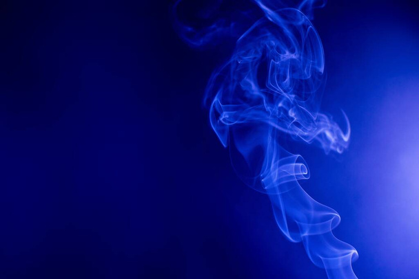 A smoke creating abstract shapes on a blue background - Foto, imagen