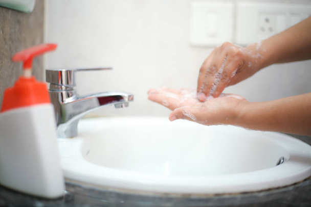細菌や感染症を防ぐために液体石鹸でやさしく手を洗う - 写真・画像