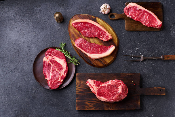 cutting boards with ribeye and striploin with picanha and chuck roll fresh black angus prime raw beef steaks on wooden background, top view - Foto, immagini