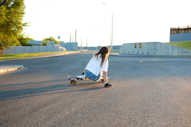 Young girl having fun with skateboard on the road. Young woman skating on a sunny day. - Fotoğraf, Görsel