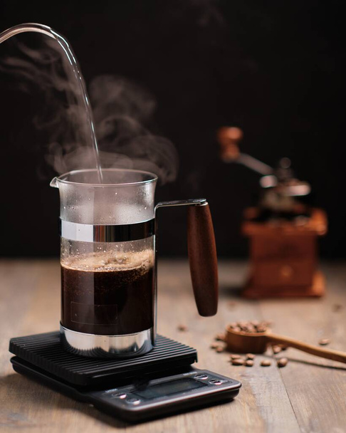 A vertical shot of a person pouring coffee in glass on a black background - 写真・画像