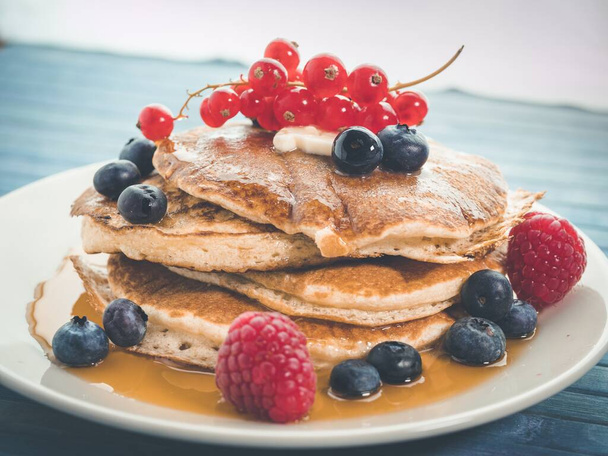 A closeup shot of a plate of delicious pancakes with caramel and berries - Foto, Bild