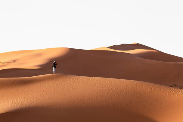 A lonely person walking in a desert near sand dunes on a sunny day - Fotografie, Obrázek