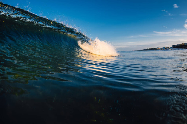 Бочка розбиває хвилю в океані з теплими тонами і пляжем
 - Фото, зображення