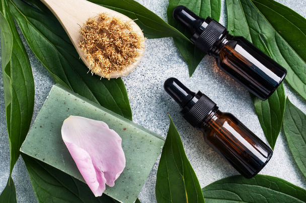 Concept SPA and Wellness. Massage brush, cosmetic oils and soap. Light background with green leaf. - Φωτογραφία, εικόνα