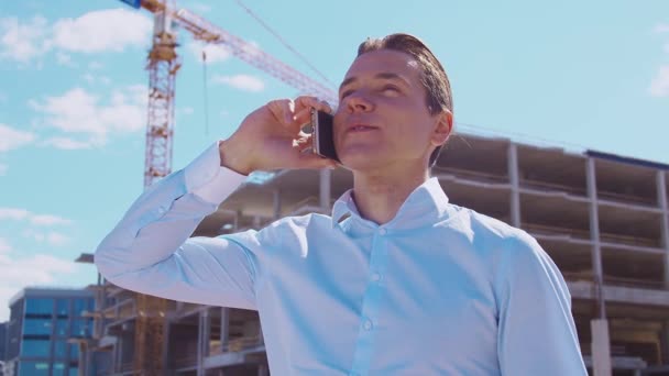 Business person standing in front of construction site. Office building and crane background. Development, real estate and investment concepts. - Video, Çekim
