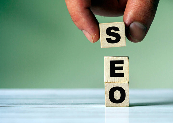 The hand puts the cube block with the inscription SEO. Seo symbol. - Foto, afbeelding
