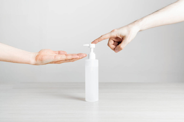 Azione della mano utilizzando spray gel disinfettante su un tavolo di sfondo bianco - Foto, immagini
