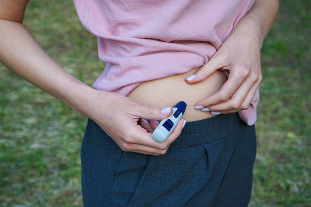 Pióro Lancet w ręce młodej kobiety robiącej test. Pojęcie cukrzycy. - Zdjęcie, obraz