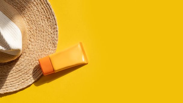 Sun protection objects. Straw woman's hat with sunscreen protection spf cream top view on bright yellow background. Beach accessory. Summer Travel Vacation Concept. Sale kit. Copy space. - Fotoğraf, Görsel