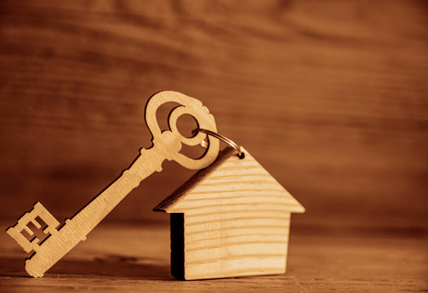 House key with trinket on wooden background, empty copy space for inscription. - Фото, зображення