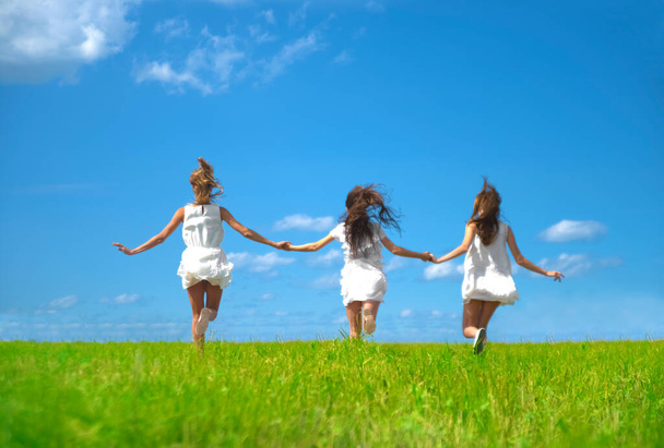 Three smiling girls running  at field  - Zdjęcie, obraz