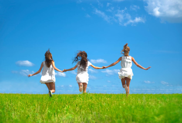 Drie lachende meisjes rennen op het veld  - Foto, afbeelding