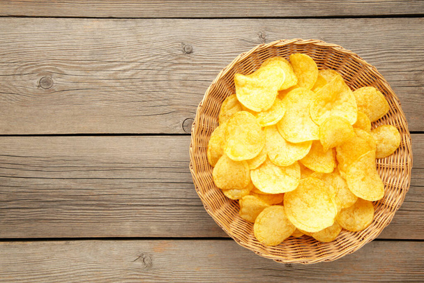 Potato chips in basket on grey wooden background. Top view - Fotó, kép