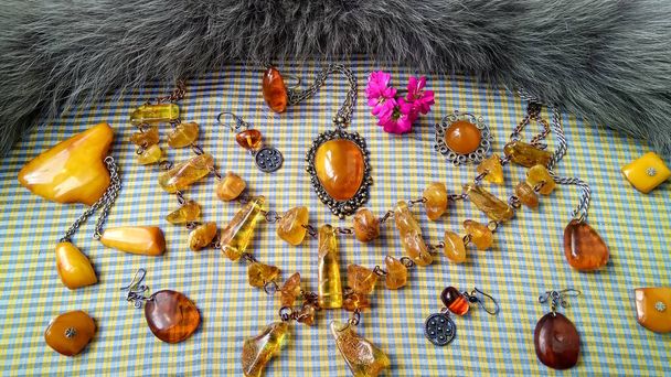 Een spectaculaire, vintage set sieraden gemaakt van natuurlijk amber ligt op een geel-blauwe zijden stof, versierd met lichtgrijs bont. - Foto, afbeelding