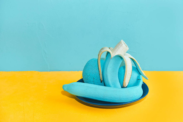 peeled banana. painted apple turquoise orange on a plate - Photo, image