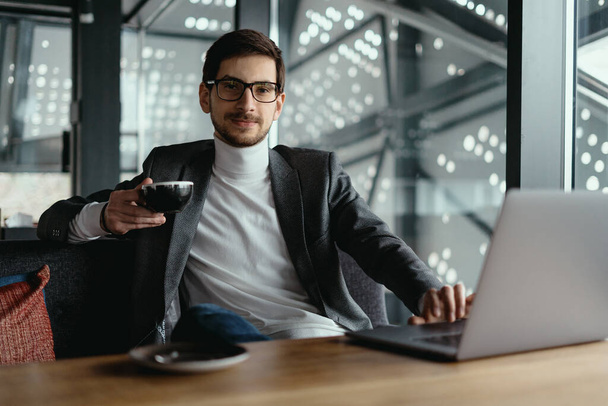 Successful business man working on laptop while drinking coffee - Valokuva, kuva