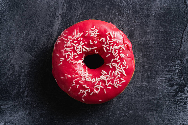 Donut rosa com polvilhas, doces alimentos de sobremesa vidros no fundo texturizado de concreto escuro, vista superior macro
 - Foto, Imagem