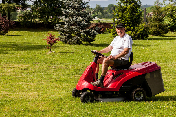 Hombre mayor conduciendo una cortadora de césped roja
 - Foto, imagen