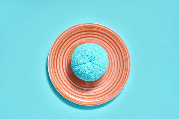 painted orange in turquoise color on an ceramic plate. creativity design concept - Фото, изображение