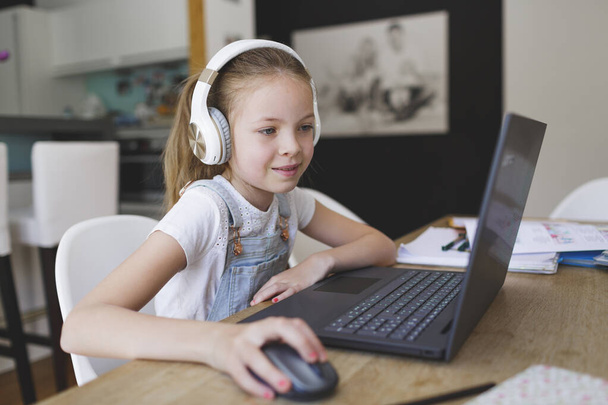 young girl with headphones and laptop is doing homeschooling - Foto, Imagem