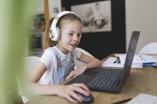 young girl with headphones and laptop is doing homeschooling - Φωτογραφία, εικόνα