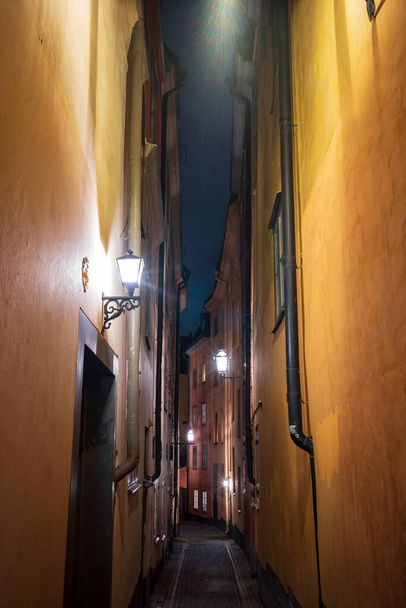 A verticle image of a narow alley in Gamla Stan, Stockholm, Sweden's old town, with colorful 17th and 18th-century buildings and cobblestone streets.  - Photo, Image