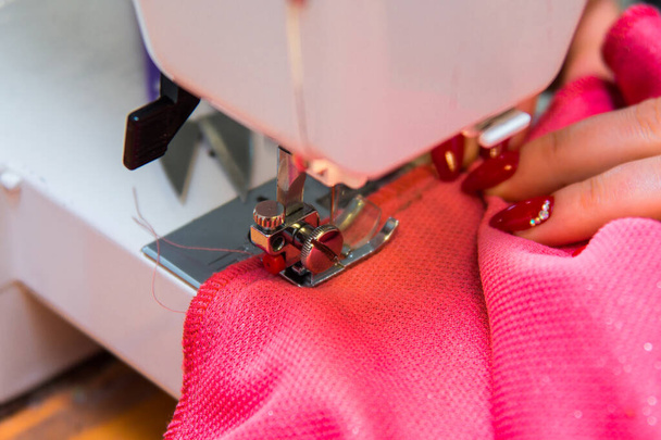 Coser ropa en un estudio de costura. Primer plano de las manos de costurera, material y aguja de una máquina de coser. Negocios en un estudio de costura
 - Foto, Imagen