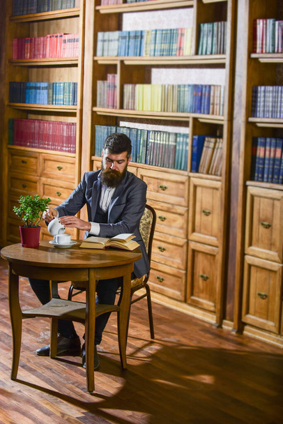 Aristocrat on thoughtful face reading book. Oldfashioned man holds cup - Фото, зображення