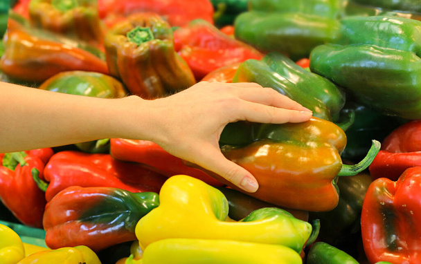 Женщина вручную выбирает перец в магазине
 - Фото, изображение