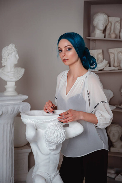 Beautiful young girl with blue hair in the sculptor's studio. Ancient art and living beauty - Photo, Image