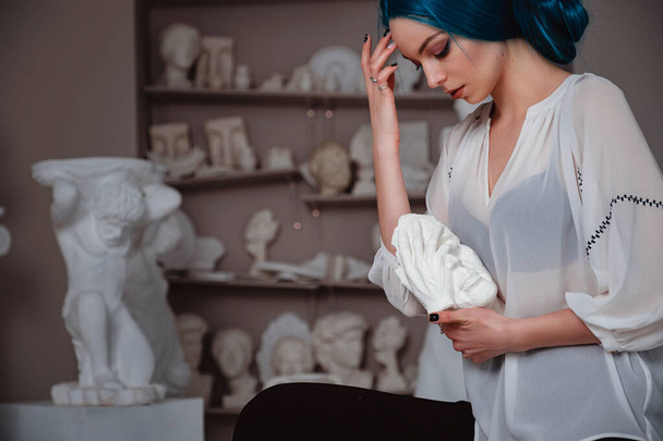 Beautiful young girl with blue hair in the sculptor's studio. Ancient art and living beauty - Photo, Image