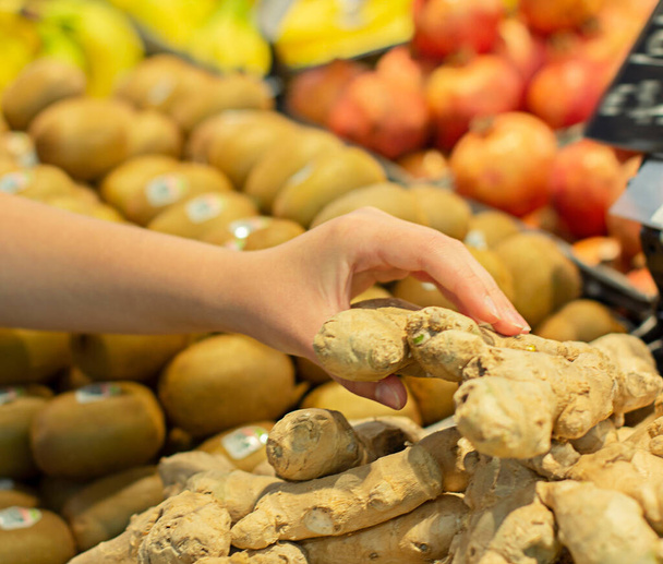 Mujer mano elegir jengibre en el supermercado
 - Foto, Imagen