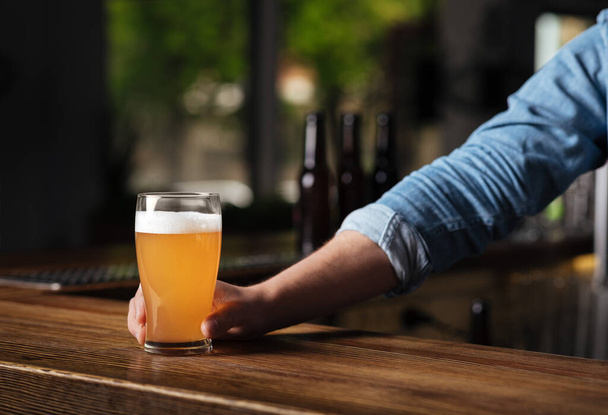 Oktoberfest en el pub. Barman mano sostiene cerveza lager en vidrio en el interior de la barra
 - Foto, imagen