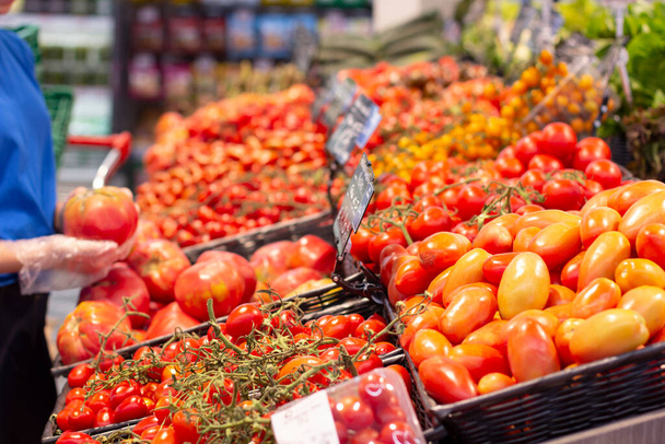 Mão feminina escolhendo tomates no supermercado
 - Foto, Imagem