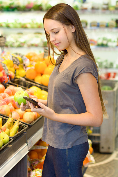 Teen girl choosing a daily products at supermarket. Reading product information.Concept of conscious choice of healthy food by teenager's. - Foto, Bild