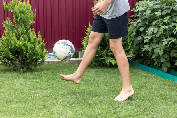 Footballer barefoot stuffs the ball on the green grass. - 写真・画像