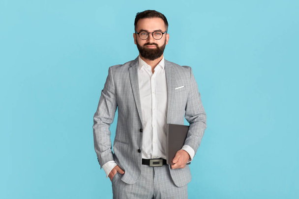 Σίγουρος ιδιοκτήτης επιχείρησης σε formalwear και γυαλιά που κατέχουν tablet υπολογιστή σε μπλε φόντο - Φωτογραφία, εικόνα
