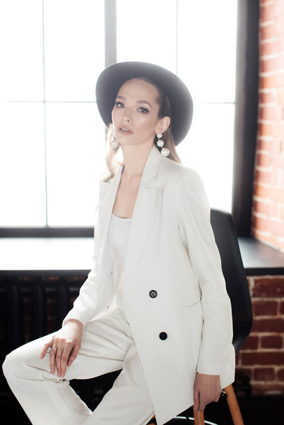Young girl in a white suit and a black hat. The concept of clothing. - Photo, Image